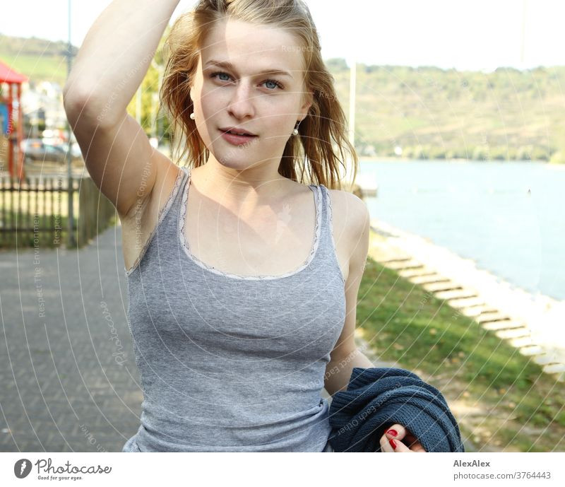 3764443-young-woman-in-a-grey-top-touches-her-long-blonde-hair-as-she-walks-along-the-rhine-p...jpeg