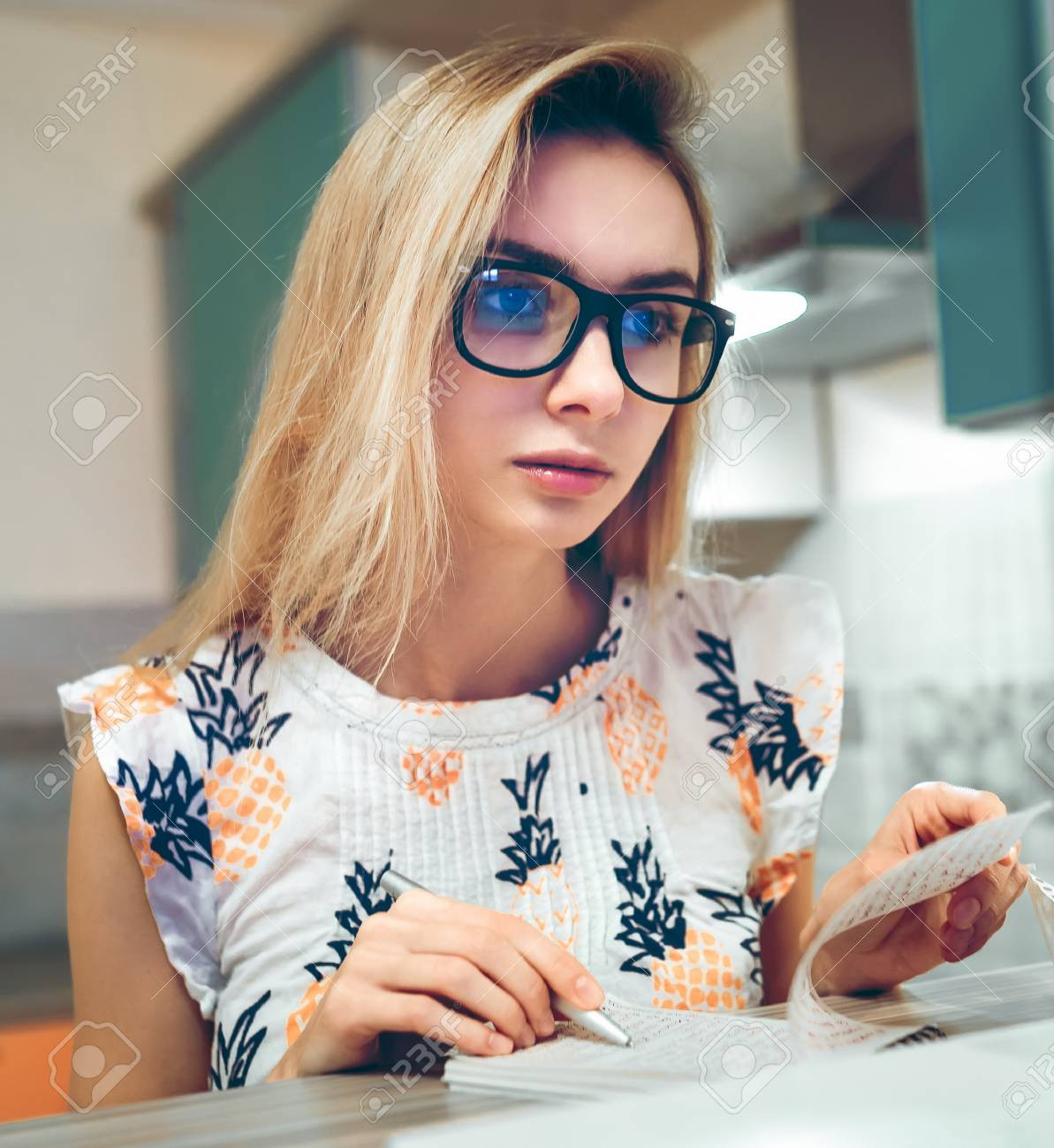 69628970-blonde-girl-wearing-glasses-sitting-at-home-writing-in-a-paper-notebook.jpg