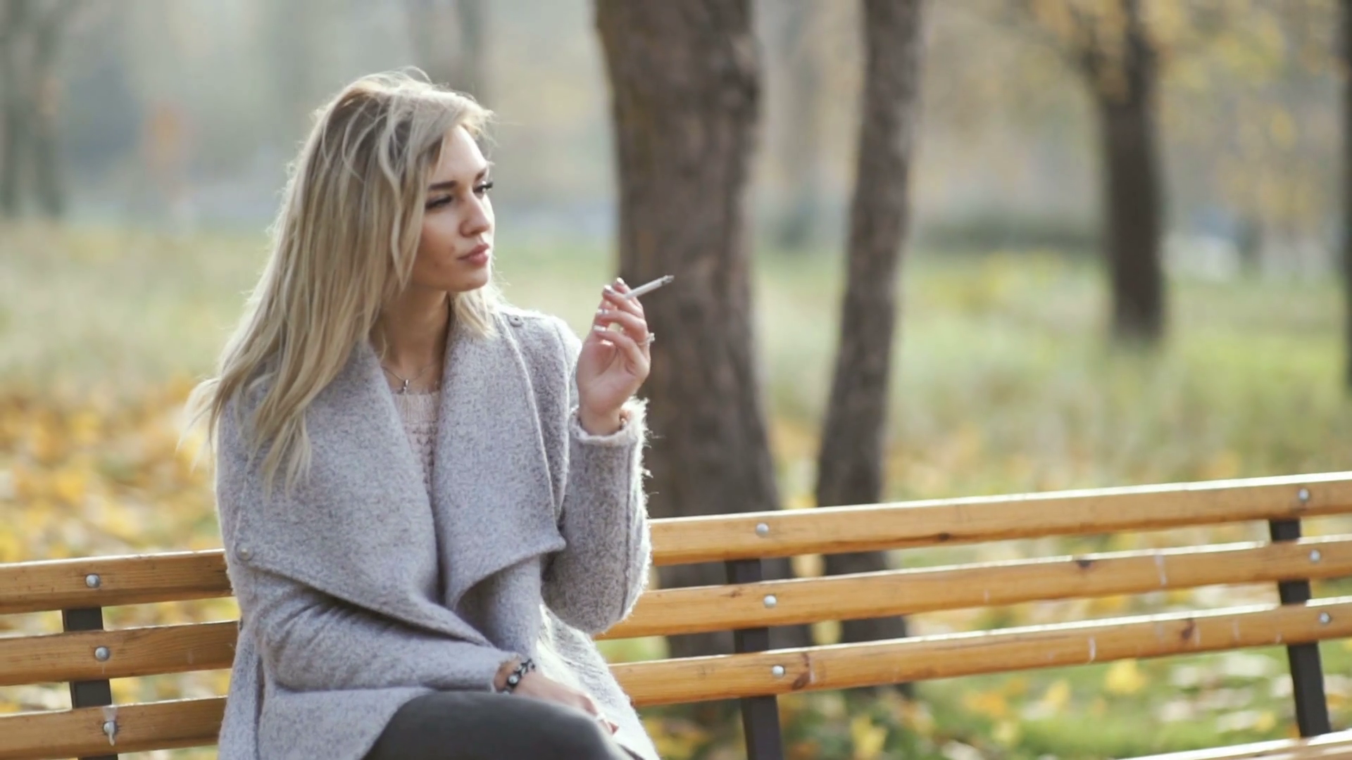 videoblocks-young-beautiful-business-woman-smoking-a-cigarette-in-the-park-autumn-background_h...png